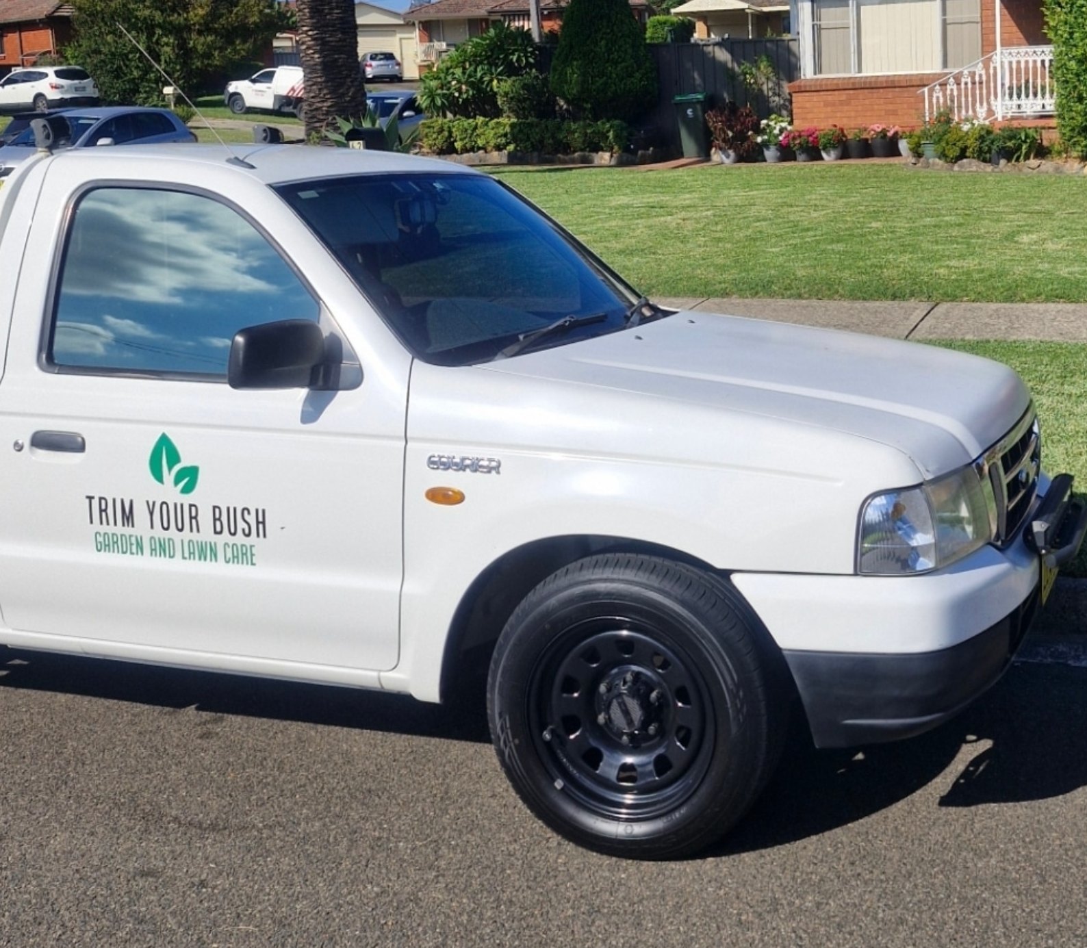 Trim Your Bush work ute parked outside a residential property with a freshly maintained lawn